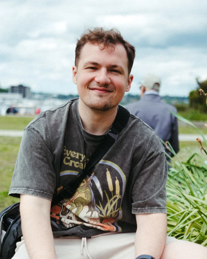 Micah smiling, sitting on the grass in a park